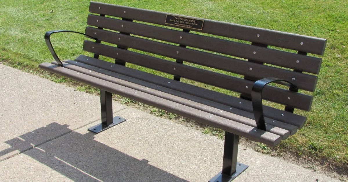 Dark brown memorial bench with black metal armrests